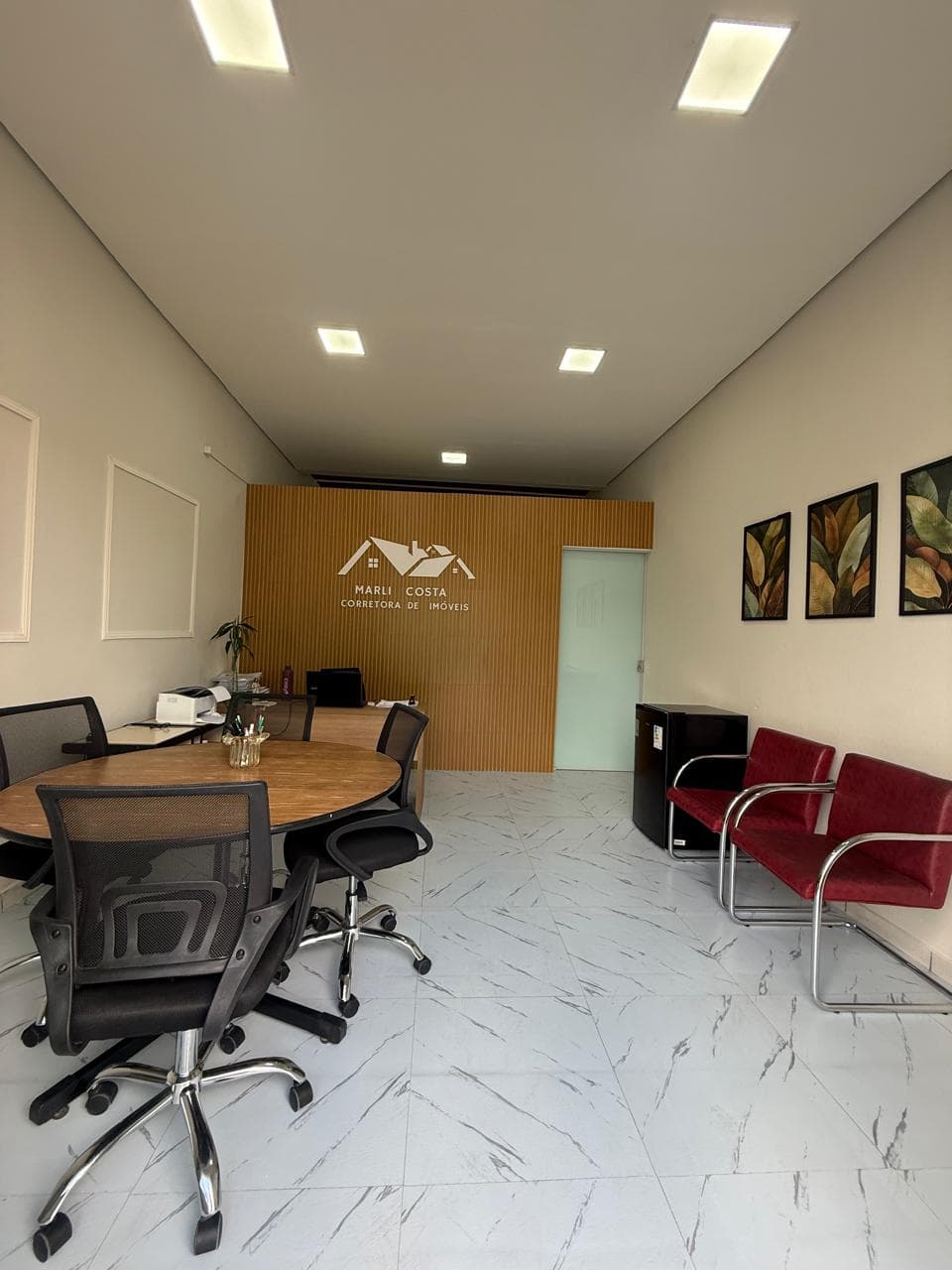 Interior da sede da Marli Corretora, com área de atendimento e a identidade da empresa ao fundo